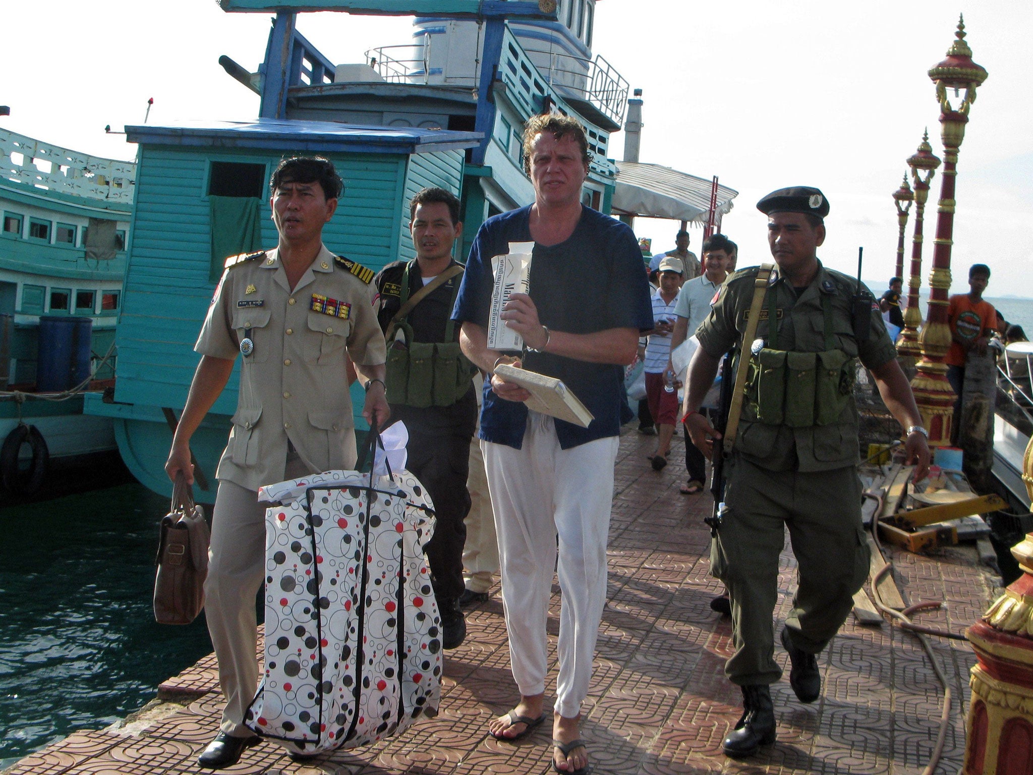 Russian tycoon Sergei Polonsky walks along with police officers after his arrest in Sihanoukville, southern Cambodia