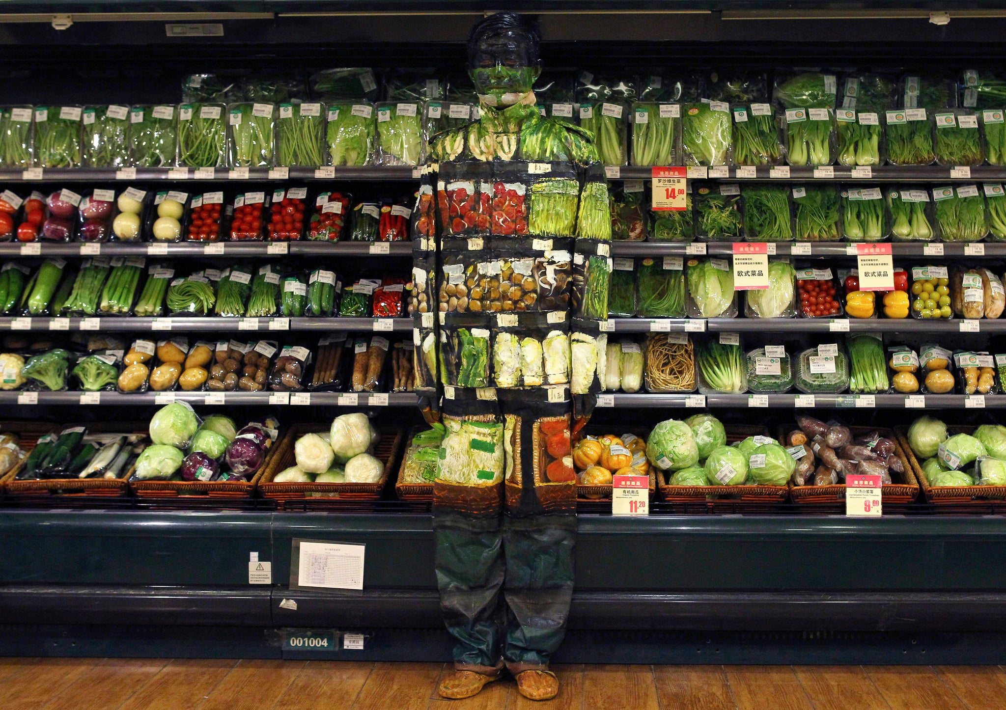 Artist Liu Bolin, also known as the 'Vanishing Artist,' demonstrates an art installation by blending in with vegetables displayed on the shelves at a supermarket in Beijing.
