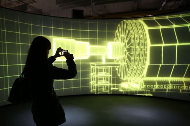 A visitor to the Science Museum takes a phone photograph of a video projection showing the workings of the Large Hadron Collider at the 'Collider' exhibition 