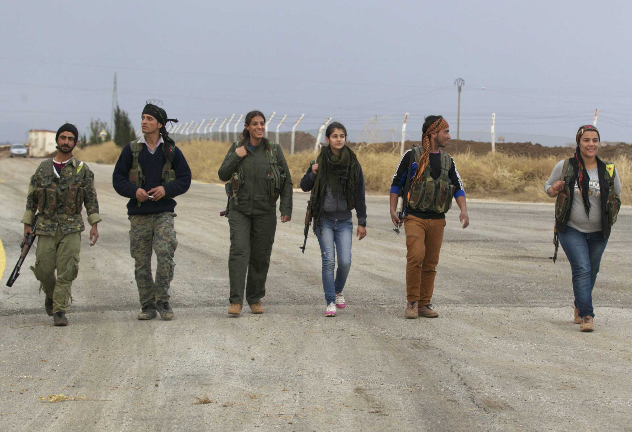 Members of the Kurdish People's Protection Units walk together in Al-Rmelan, Qamshli province