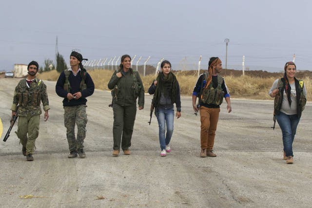 Members of the Kurdish People's Protection Units walk together in Al-Rmelan, Qamshli province