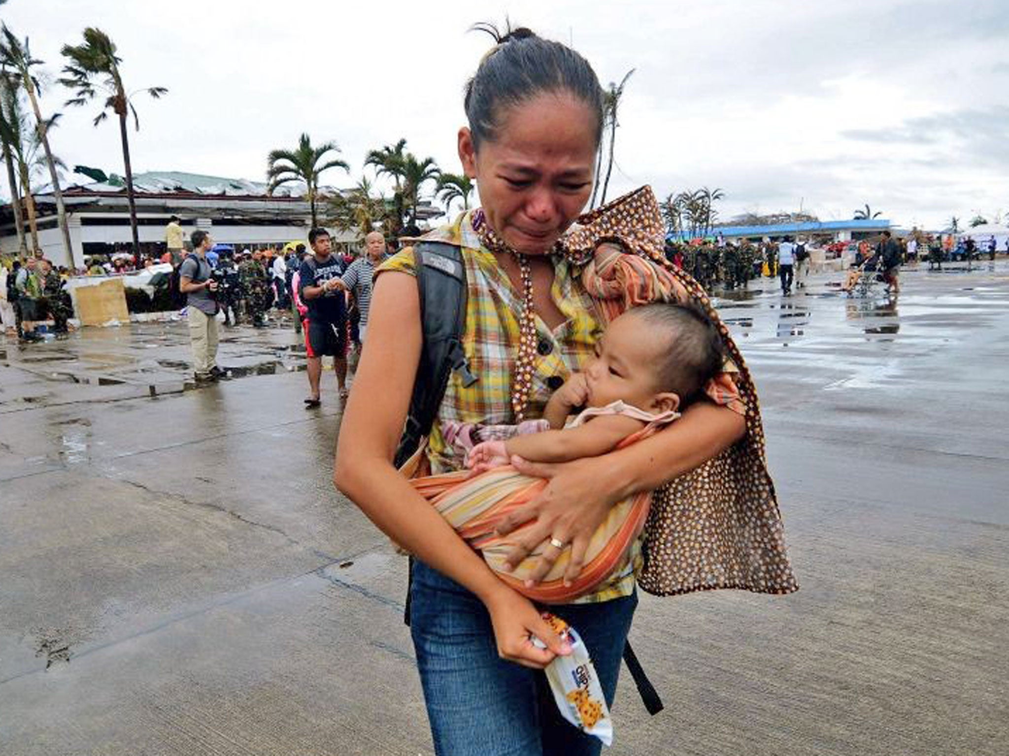 A woman weeps as she carries a child to a military aircraft to evacuate the area which has been devastated by Typhoon Haiyan