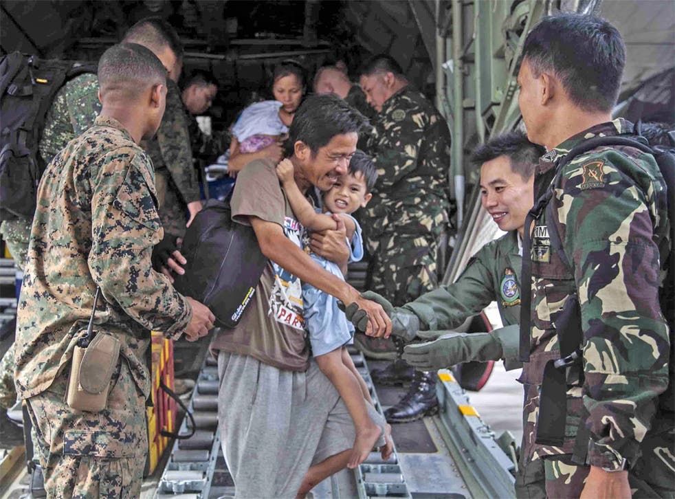 A US Marine and members of the Philippine Armed Forces help displaced civilians
