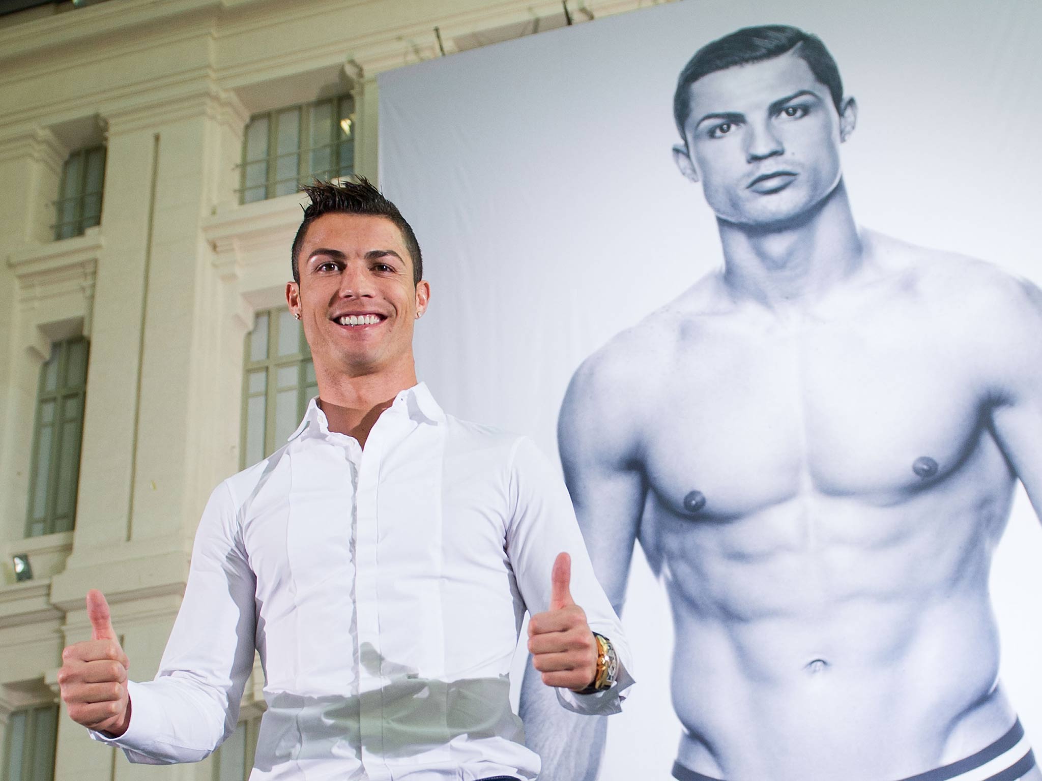 Cristiano Ronaldo poses in front of an advert of him wearing his new range of underpants