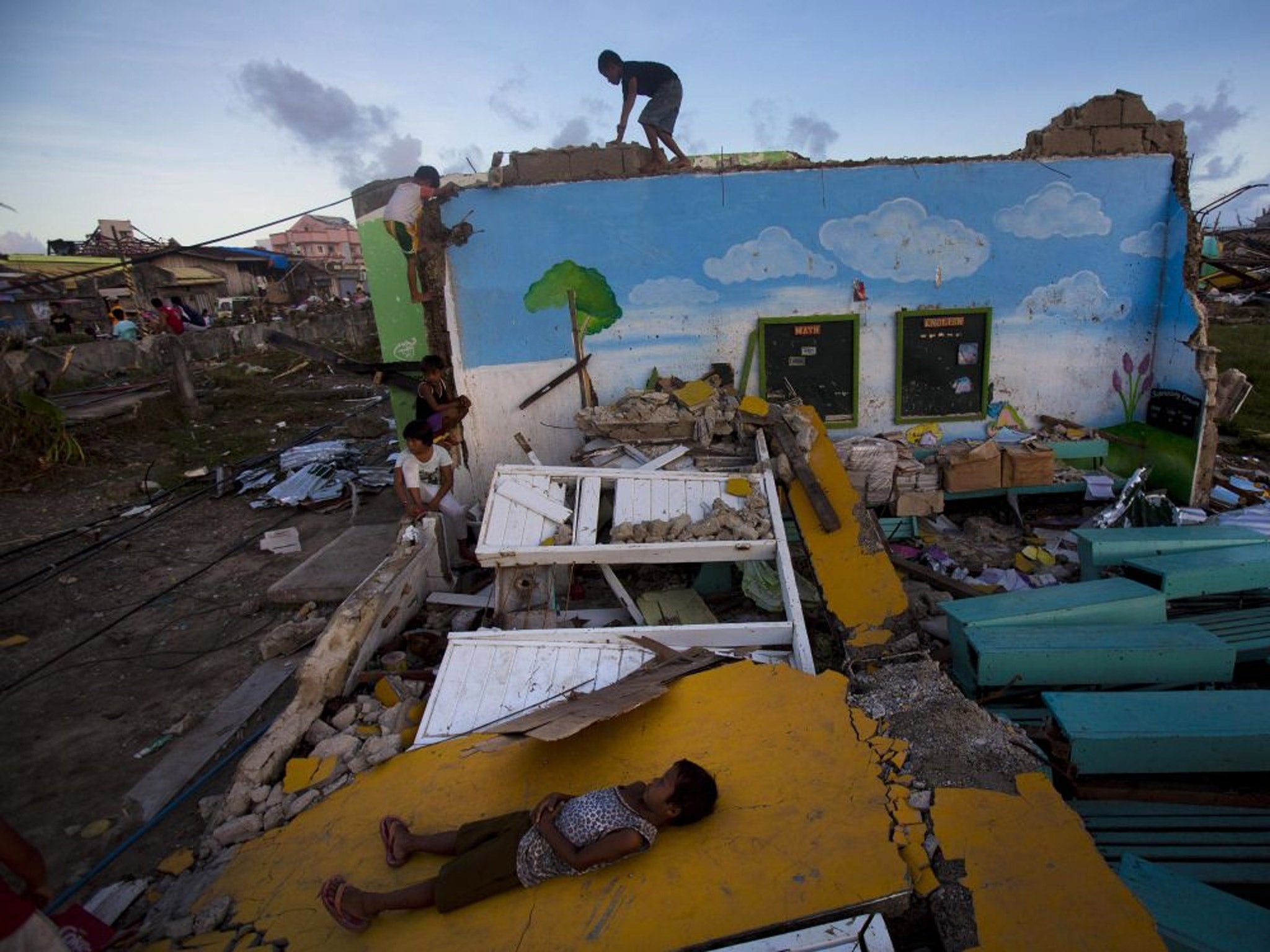 Children who survived Typhoon Haiyan play on top of the ruins of their destroyed primary school in Guiuan, Philippines