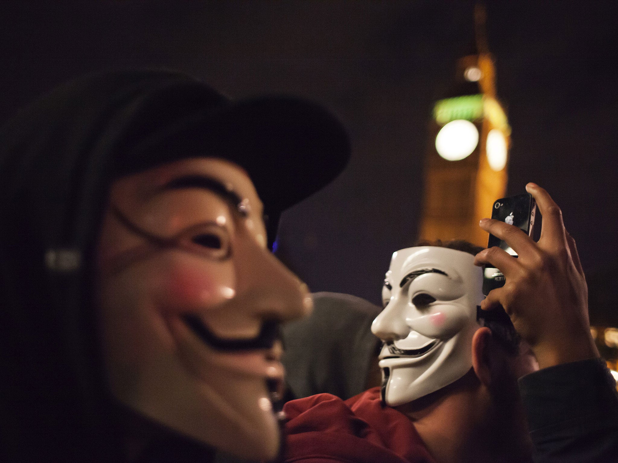 Protestors in the UK are seen wearing the Guy Fawkes mask commonly associated with the Anonymous group.