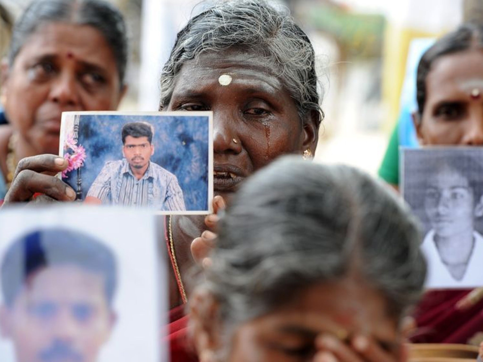 Sri Lankan mothers from the 'Dead and Missing Person's Parents' organisation hold photographs as they takes part in a protest in Jaffna