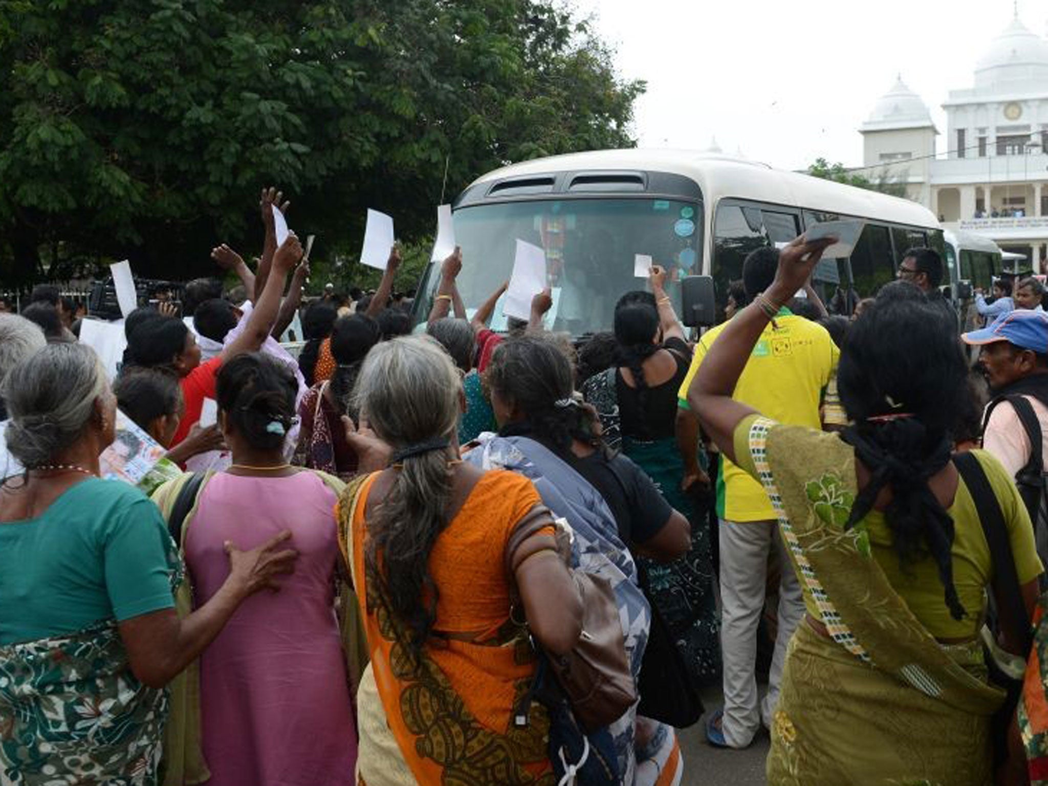 Sri Lankan ethnic Tamil women approach the media bus travelling with British Prime Minister David Cameron during a protest in Jaffna, some 400 kilometres (250 miles) north of Colombo on November 15, 2013.