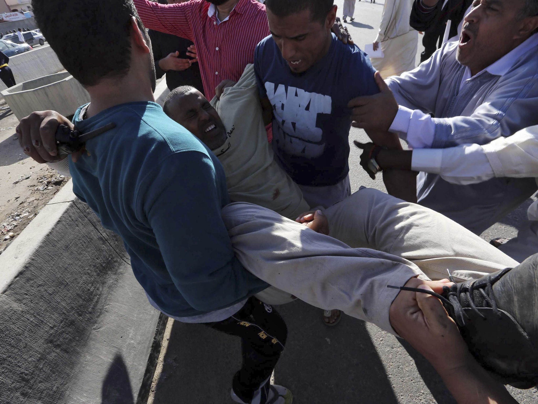 People carry an injured man after militiamen opened fire into hundreds of protesters