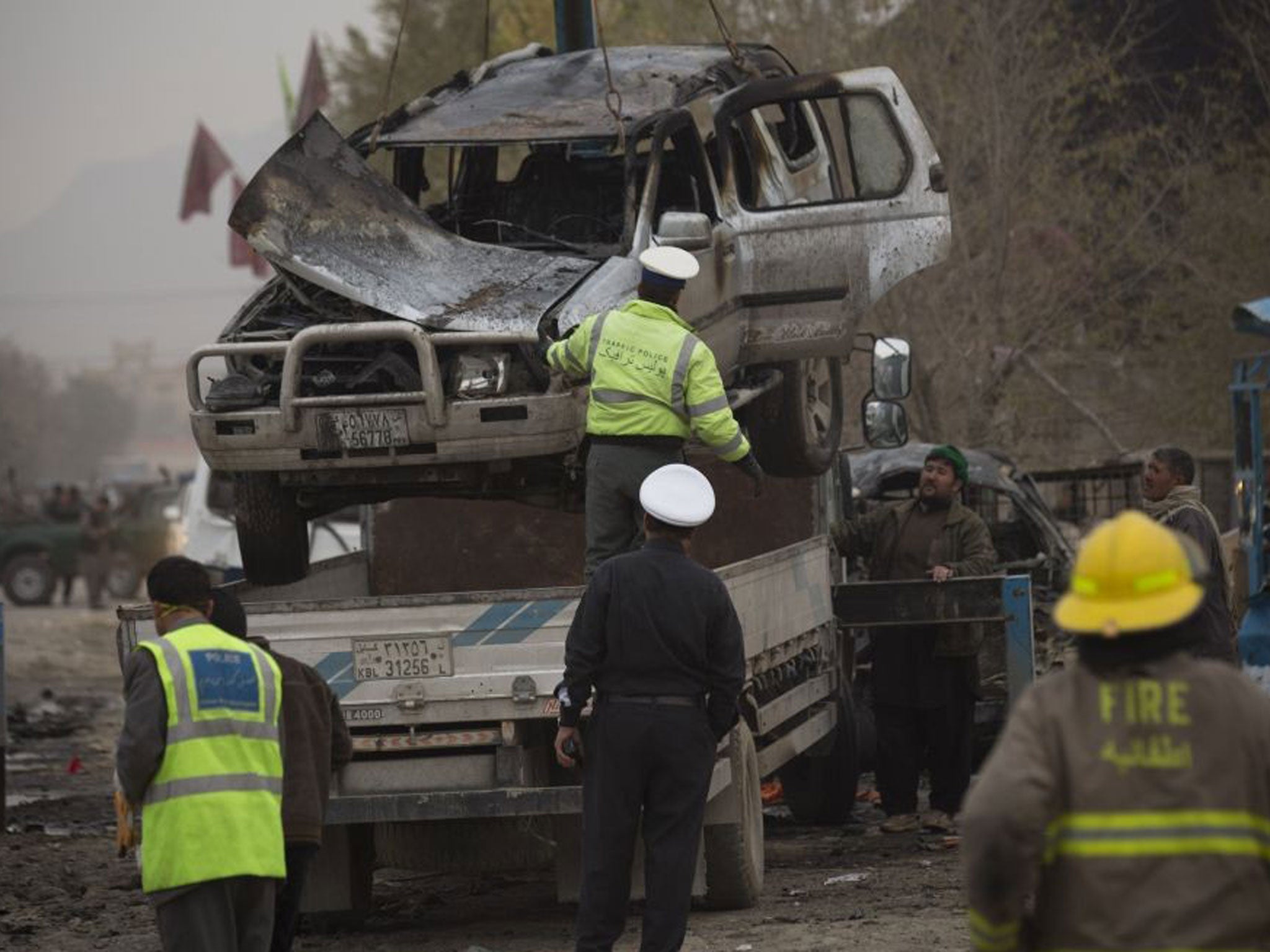 Afghan policemen remove a damaged car after a powerful suicide vehicle bomb tore through the outskirts of Kabul