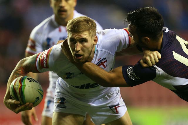 England’s Sam Tomkins, left, is tackled by France’s Éloi Pélissier, right