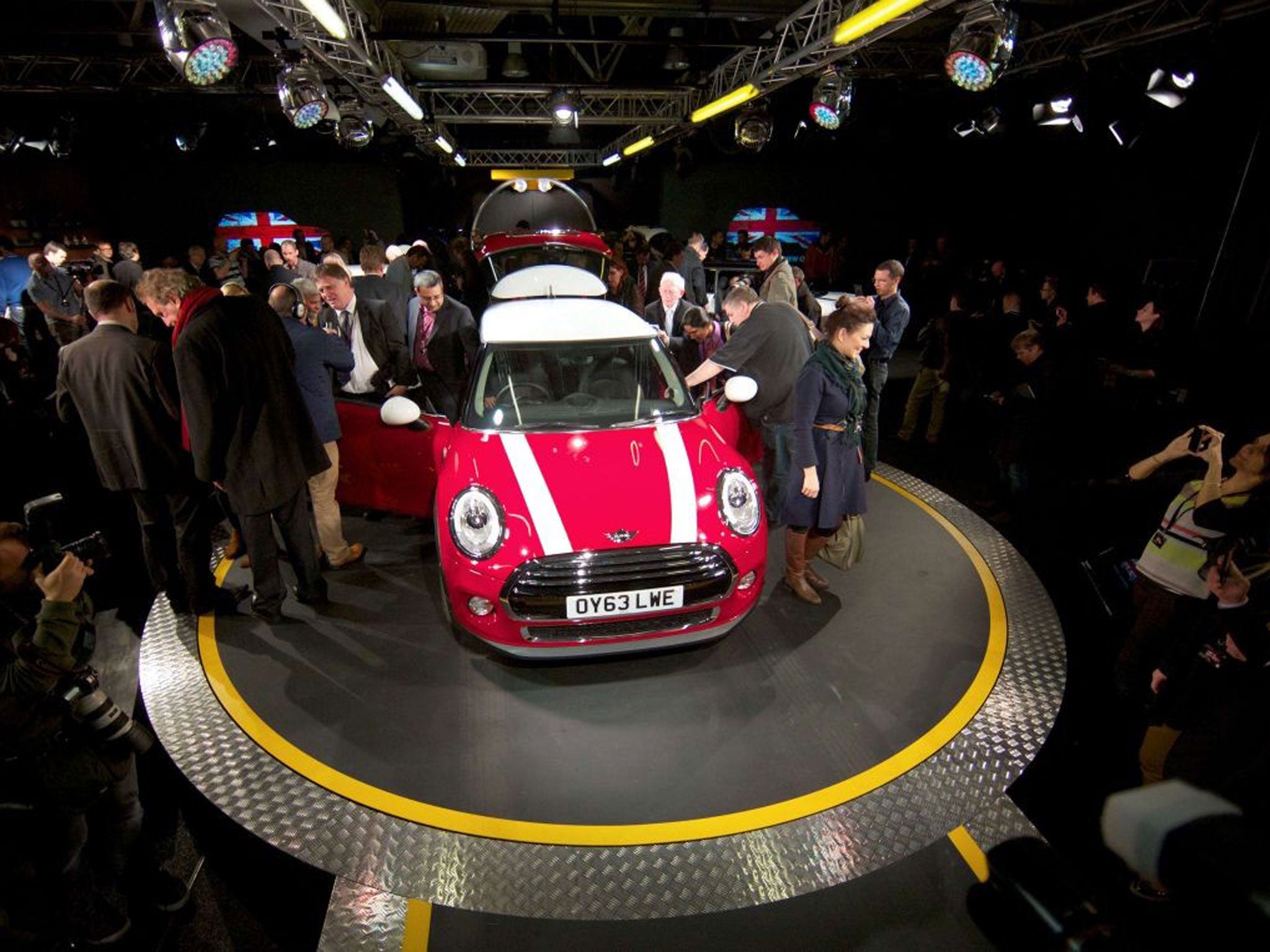 Journalists inspect the new Mini Cooper during its official unveiling at BMW's plant at Cowley in Oxford, England