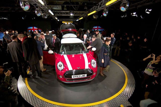 Journalists inspect the new Mini Cooper during its official unveiling at BMW's plant at Cowley in Oxford, England