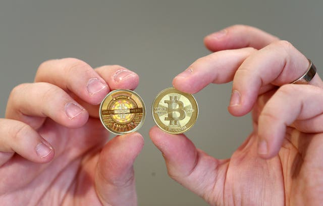 Software engineer Mike Caldwell shows the front (R) and back, hologram side, (L) of a physical Bitcoin he minted in his shop on April 26, 2013 in Sandy.