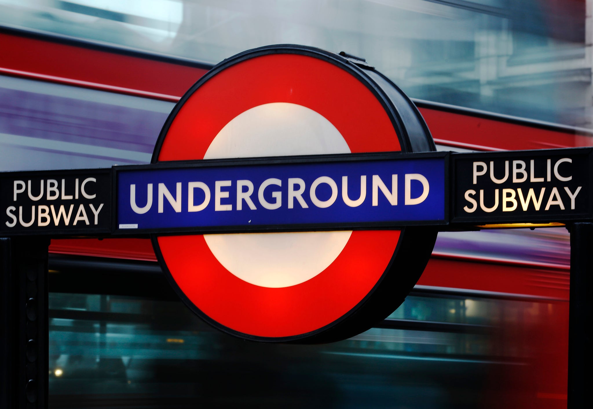 A bus passes a sign for the London Underground tube system in London.