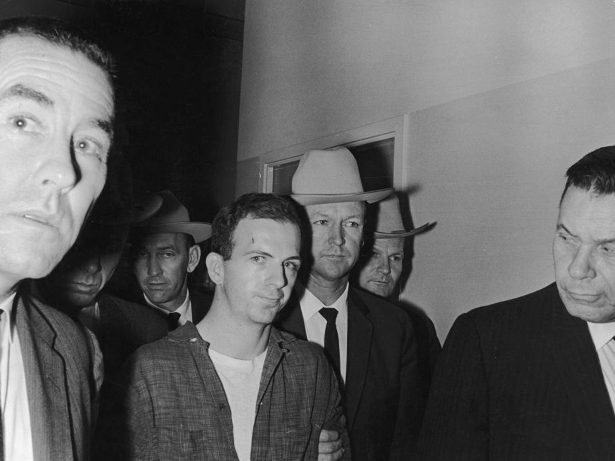 Lee Harvey Oswald is led through the basement of Dallas Police Headquarters in advance of his transfer to the county jail