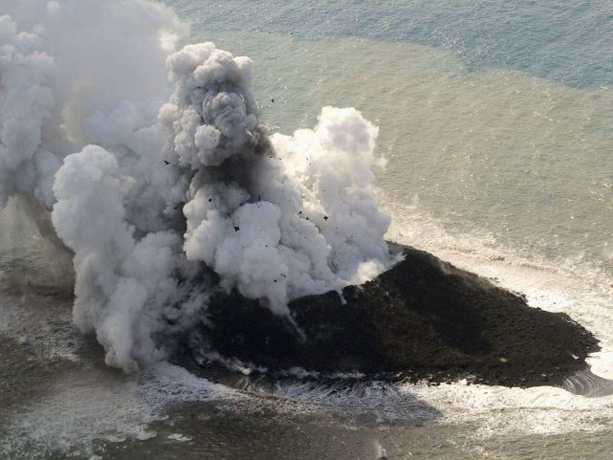 Smoke from an erupting undersea volcano forms a new island off the coast of Nishinoshima