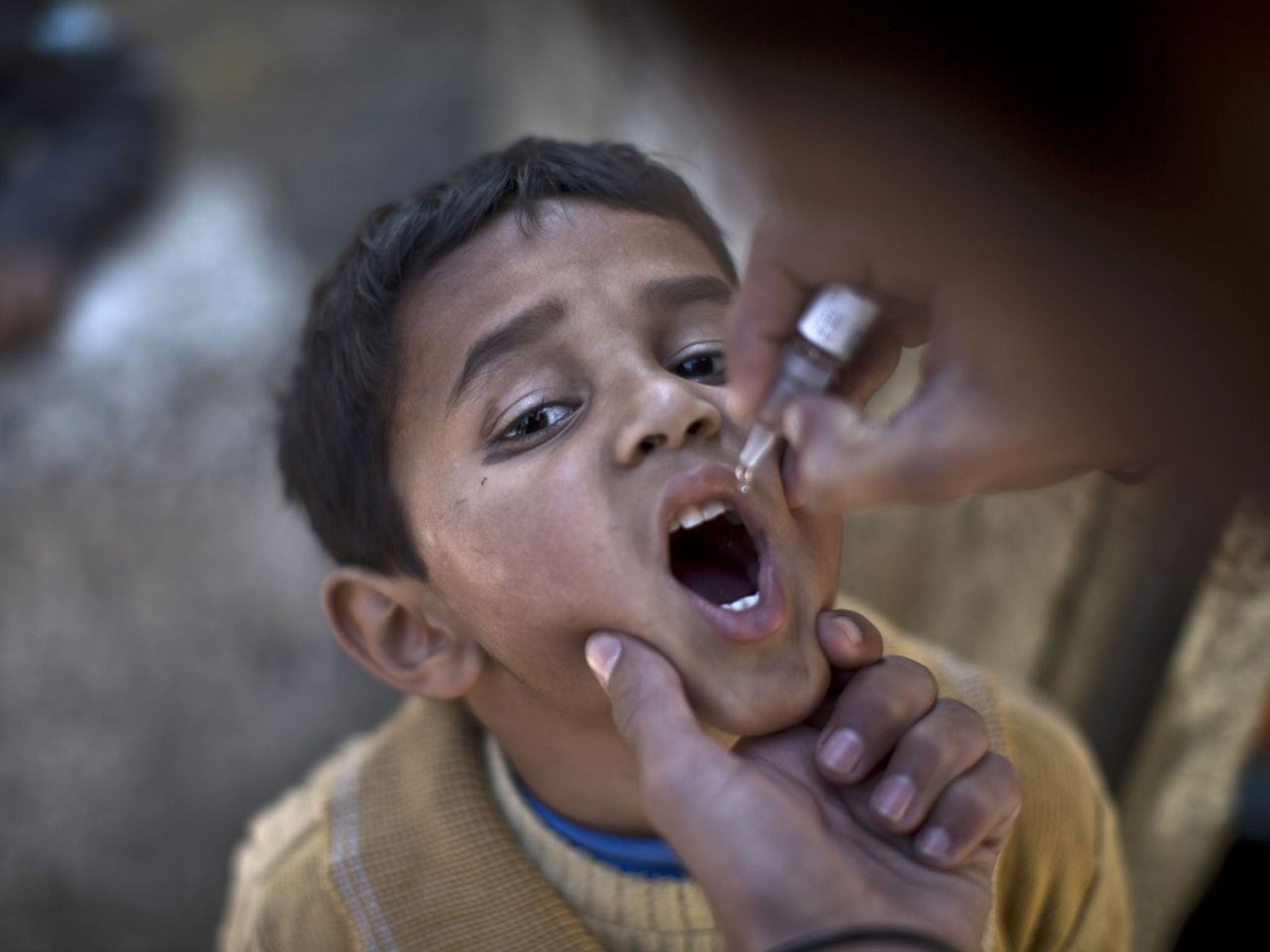 A Pakistani child is vaccinated against polio by a health worker in Islamabad, Pakistan