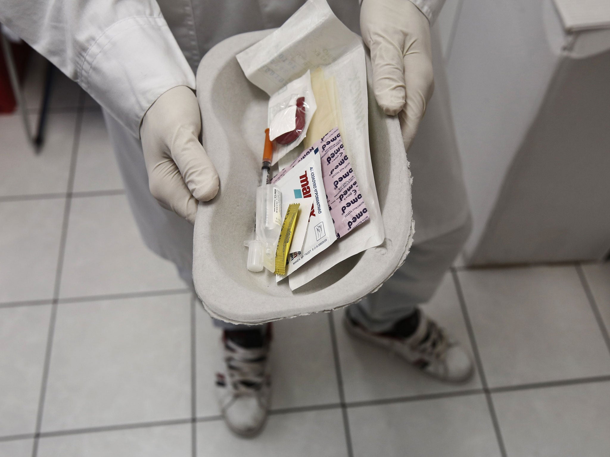 A paramedic holds a kit containing syringes, bandaids and antiseptic pads which are going to be used by drug addicts inside a supervised injection room in Athens