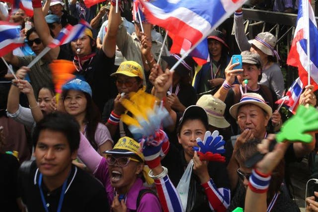 Anti-government protesters blow whistles and wave national flags as they gather outside the Industry Ministry in Bangkok