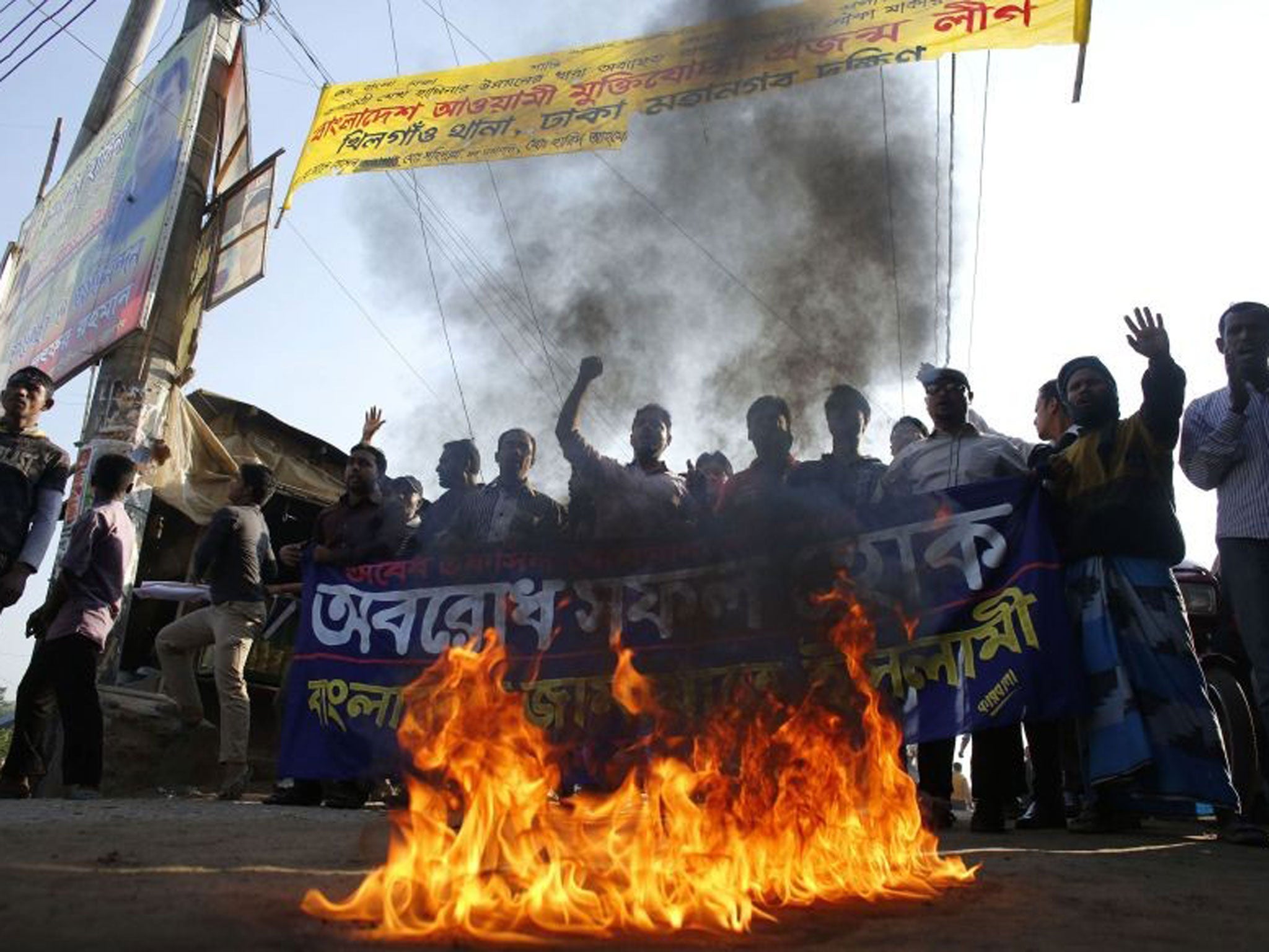 Activists of Bangladesh Jamaat-e Islami shout slogans as they set a fire on a street during a nationwide protest in Dhaka