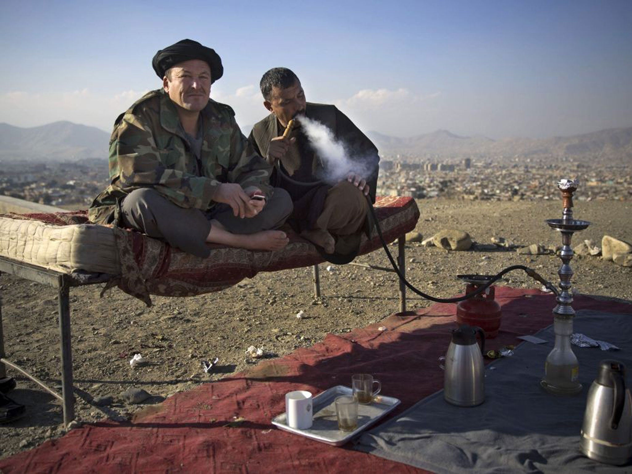 Afghan policemen enjoy a quiet moment as they smoke a water pipe on their checkpoint overlooking Kabul, Afghanistan