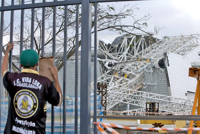 A fan inspects the damage at the partly finished Arena Corinthians in Sao Paulo, where two people died in an accident