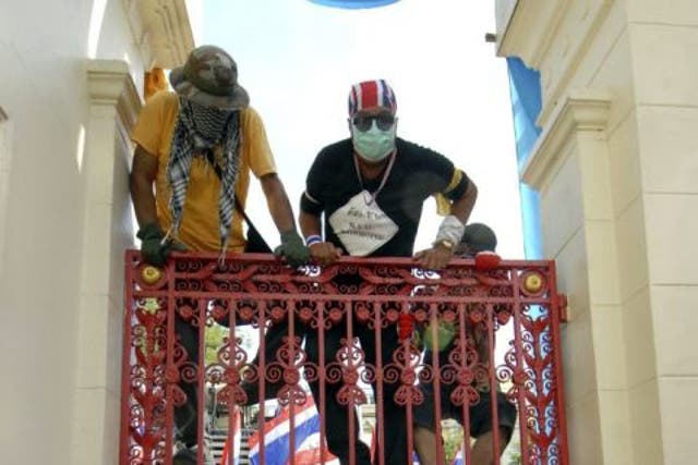 Thai anti-government protesters climb a gate into the Royal Thai Army Headquarters in Bangkok, Thailand