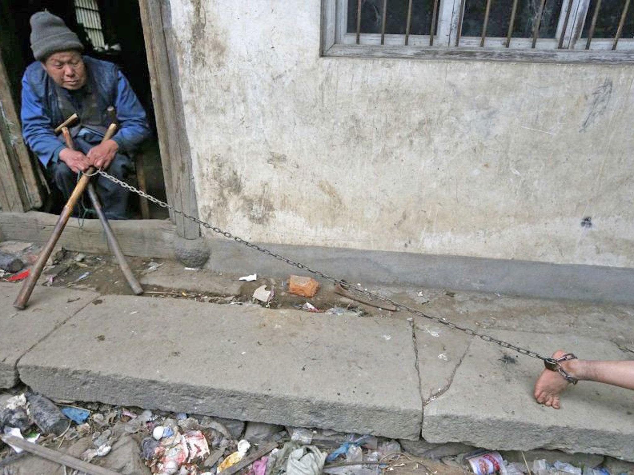 Chained Zili is looked after by his paralyzed grandfather as his plays outside their home in China