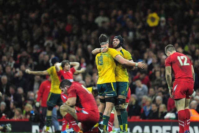 A disconsolate Wales team can't bare to look as Australia celebrate their win at the Millennium Stadium
