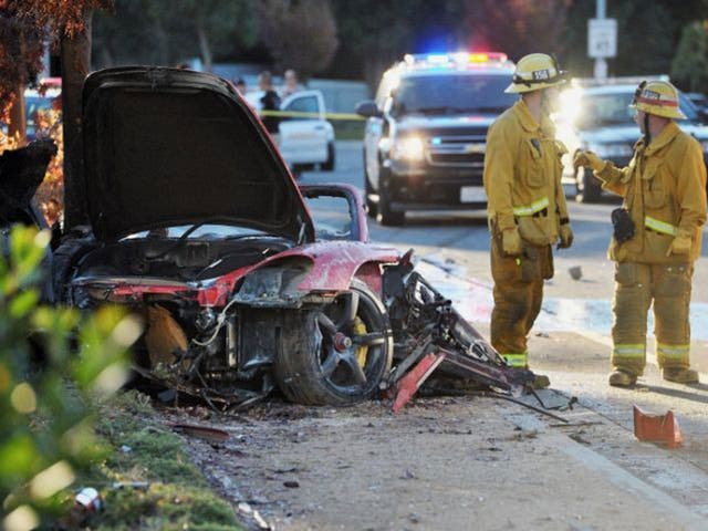 Sheriff's deputies work near the wreckage of a Porsche that crashed into a light pole