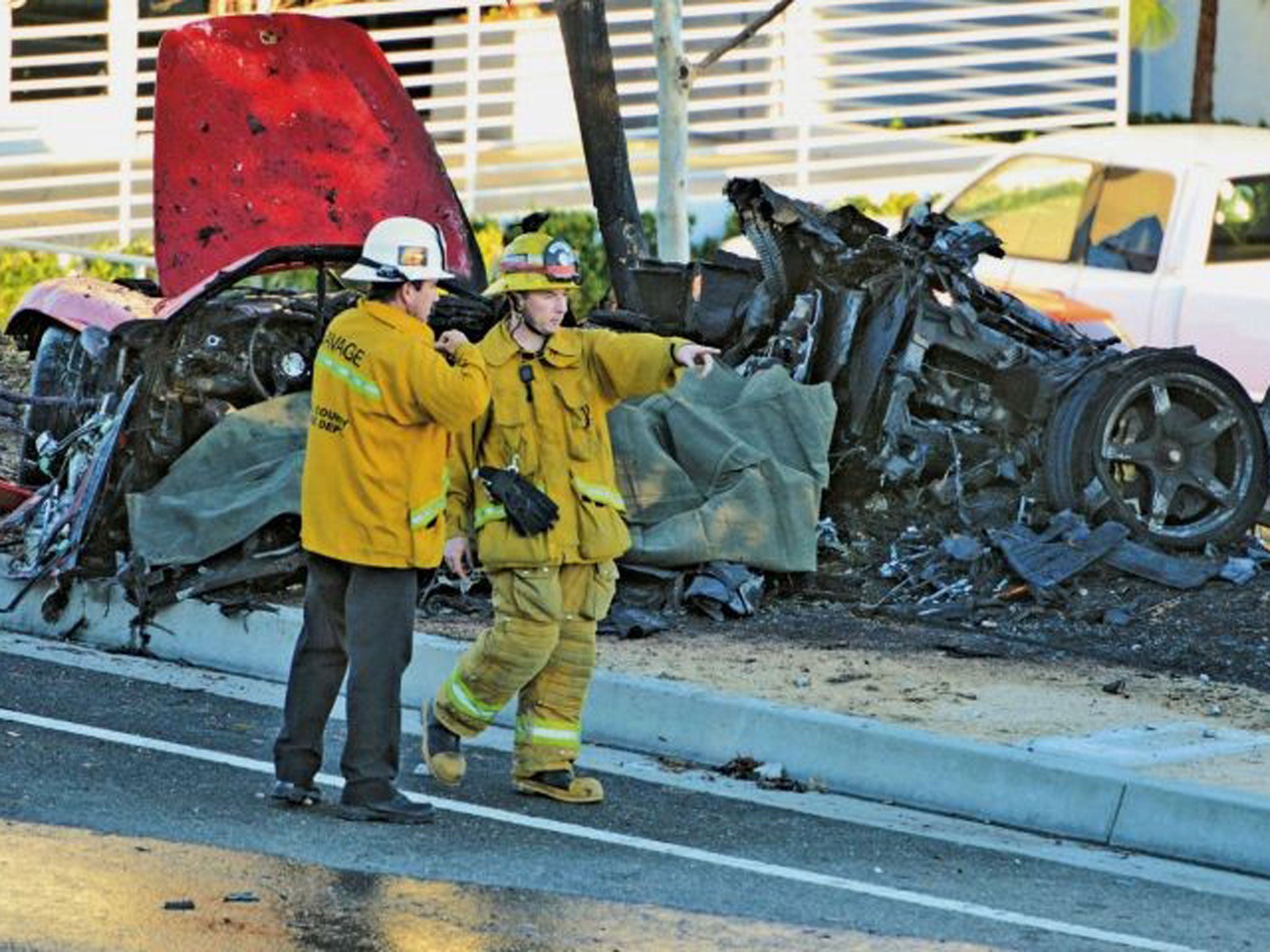 Sheriff's deputies work near the wreckage of a Porsche that crashed into a light pole on Hercules Street near Kelly Johnson Parkway in Valencia, California, north of Los Angeles