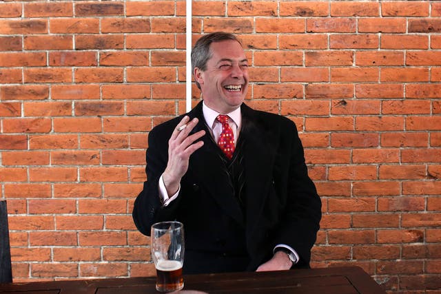Nigel Farage smokes a cigarette and drinks a pint of beer as he takes a break in a pub during the by-election campaign for Eastleigh, Hampshire