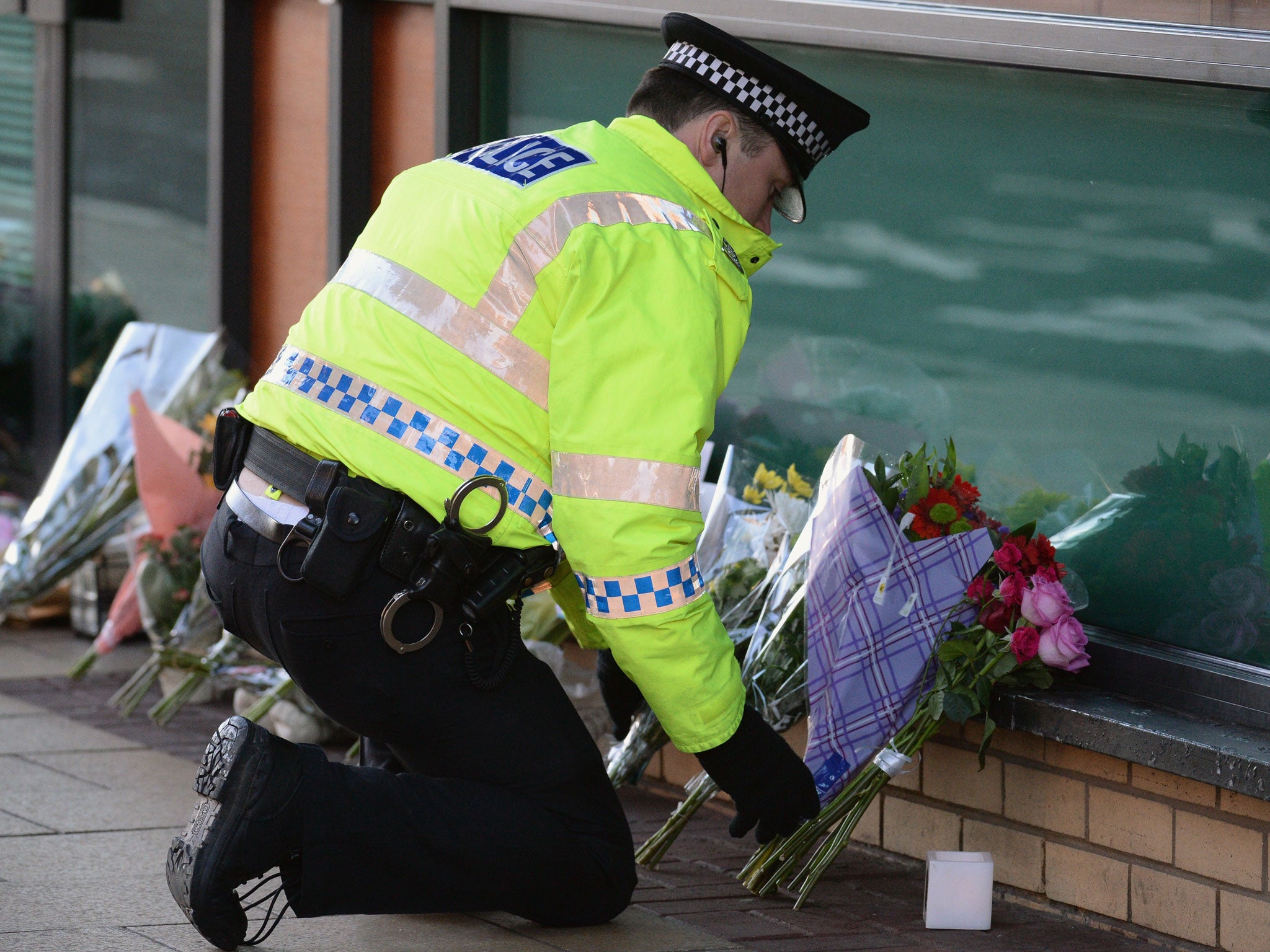 A police officer lays flowers near to The Clutha bar in Stockwell Street where a police helicopter crashed on the banks of the River Clyde
