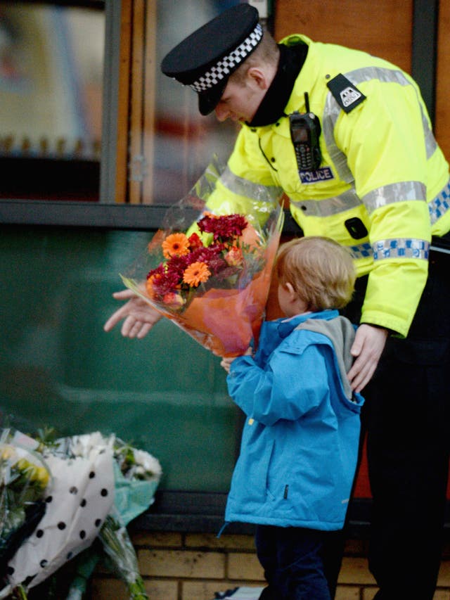 A police officer escorts a young boy as he lays flowers near to The Clutha bar in Stockwell Street where a police helicopter crashed on the banks of the River Clyde