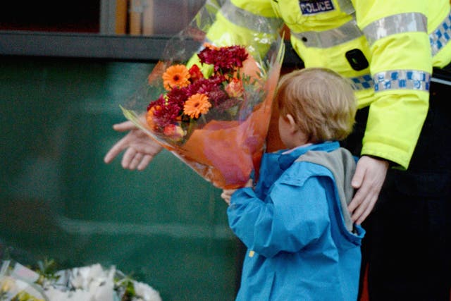 A police officer escorts a young boy as he lays flowers near to The Clutha bar in Stockwell Street where a police helicopter crashed on the banks of the River Clyde