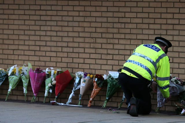 A police officer lays flowers near the scene of a helicopter crash in Glasgow city centre