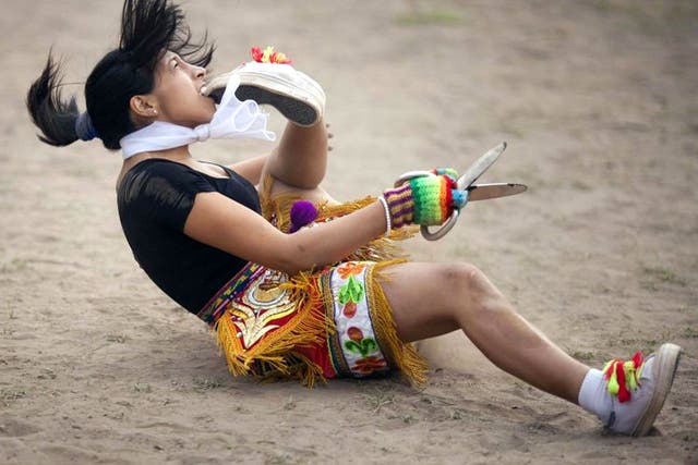 A 'scissors' dancer grabs her shoe with her mouth while performing in a national scissors dance competition in the outskirts of Lima, Peru
