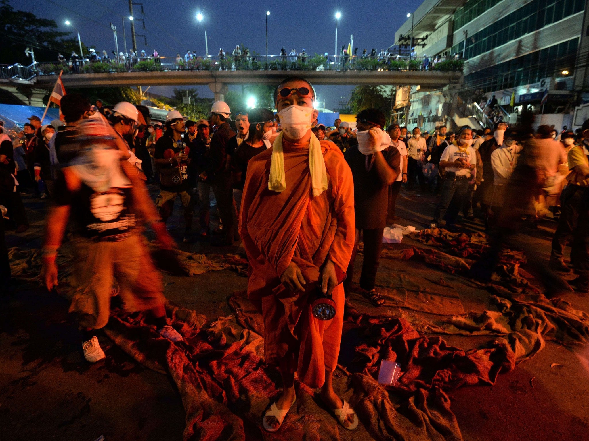 A Buddhist monk stands with protesters near Government House in Bangkok