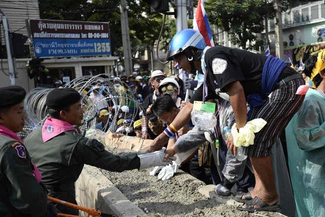 Thai riot police greet anti-government protesters as they welcome them inside their cordon