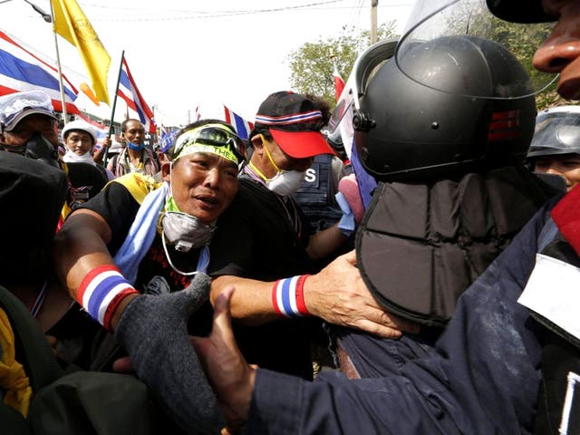A Thai anti-government protester reaches to shake hands with policemen as they jubilate the end of fighting as they enter the Municipal Police Bureau and march into the Government House after days of violence in Bangkok, Thailand
