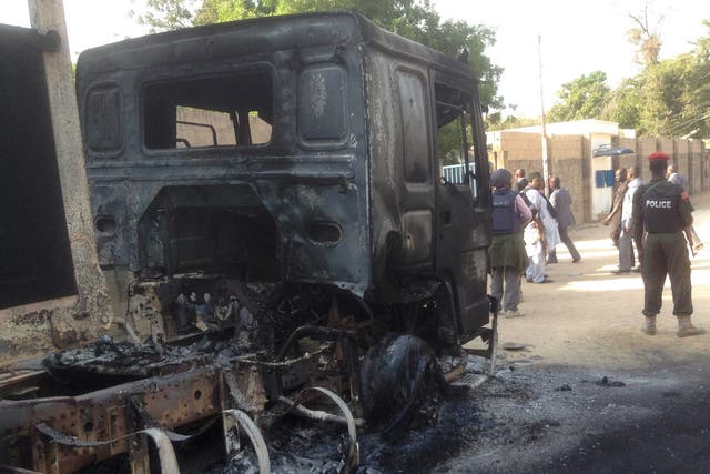 Policemen stand guard at a burnt-out truck following the attack