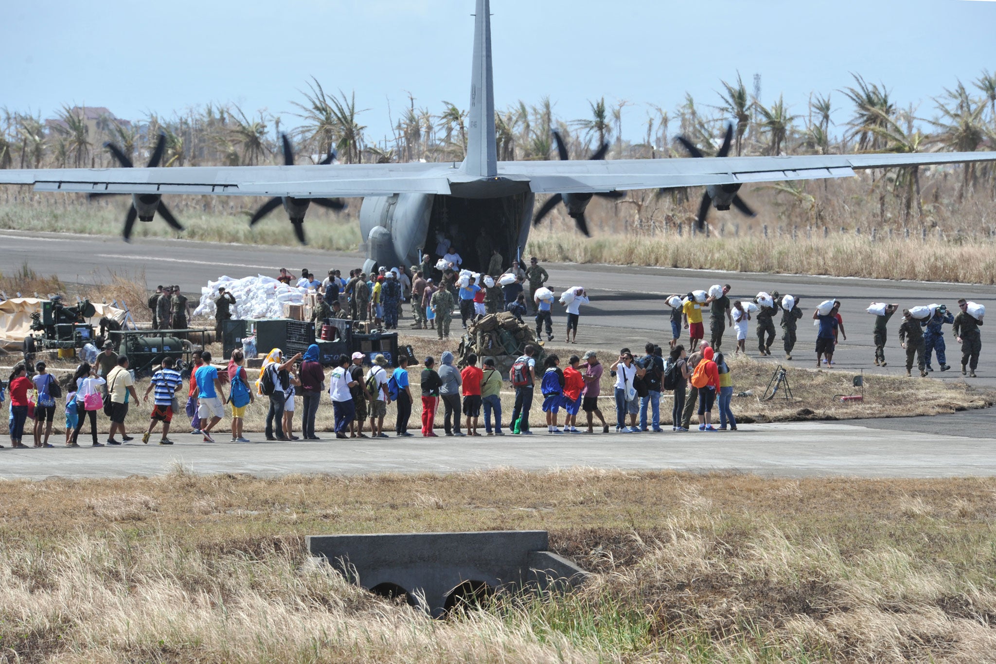 A crowd gathers on the airstrip in Guiuan as a US plane delivers aid in the aftermath of Typhoon Haiyan