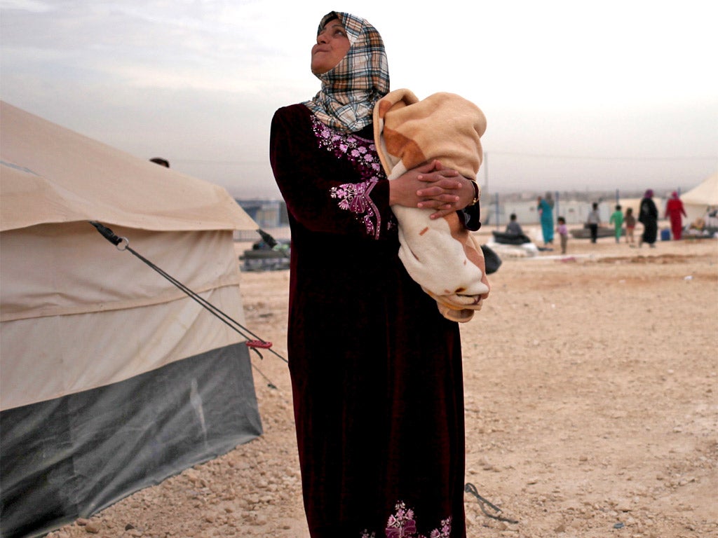 A Syrian mother holds her child at a refugee camp, near the Syrian border, in Mafraq, Jordan