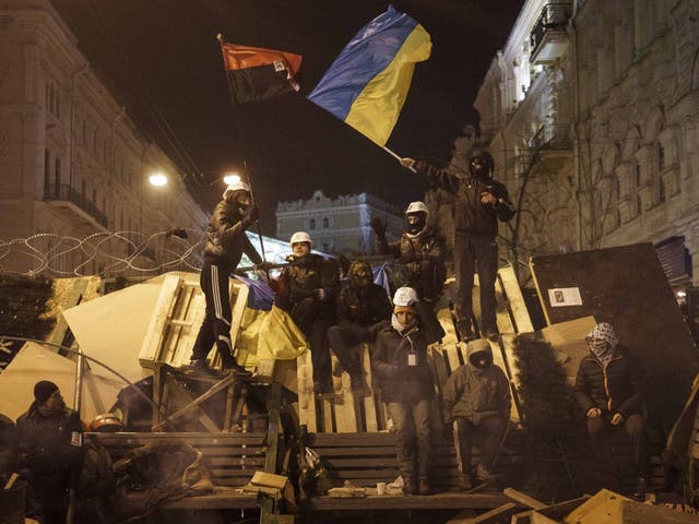 Protesters stand on a barricade as anti-government protesters gather in Independence Square