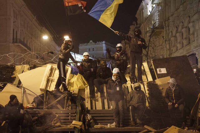 Protesters stand on a barricade as anti-government protesters gather in Independence Square