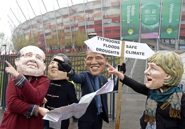 Activists wearing masks featuring France's President Francois Hollande, Japanese Prime Minister Shinzo Abe,United States President Barack Obama and Germany's Chancellor Angela Merkel discuss which climat option to take in front of the National Stadium hos
