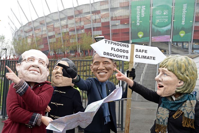 Activists wearing masks featuring France's President Francois Hollande, Japanese Prime Minister Shinzo Abe,United States President Barack Obama and Germany's Chancellor Angela Merkel discuss which climat option to take in front of the National Stadium hos