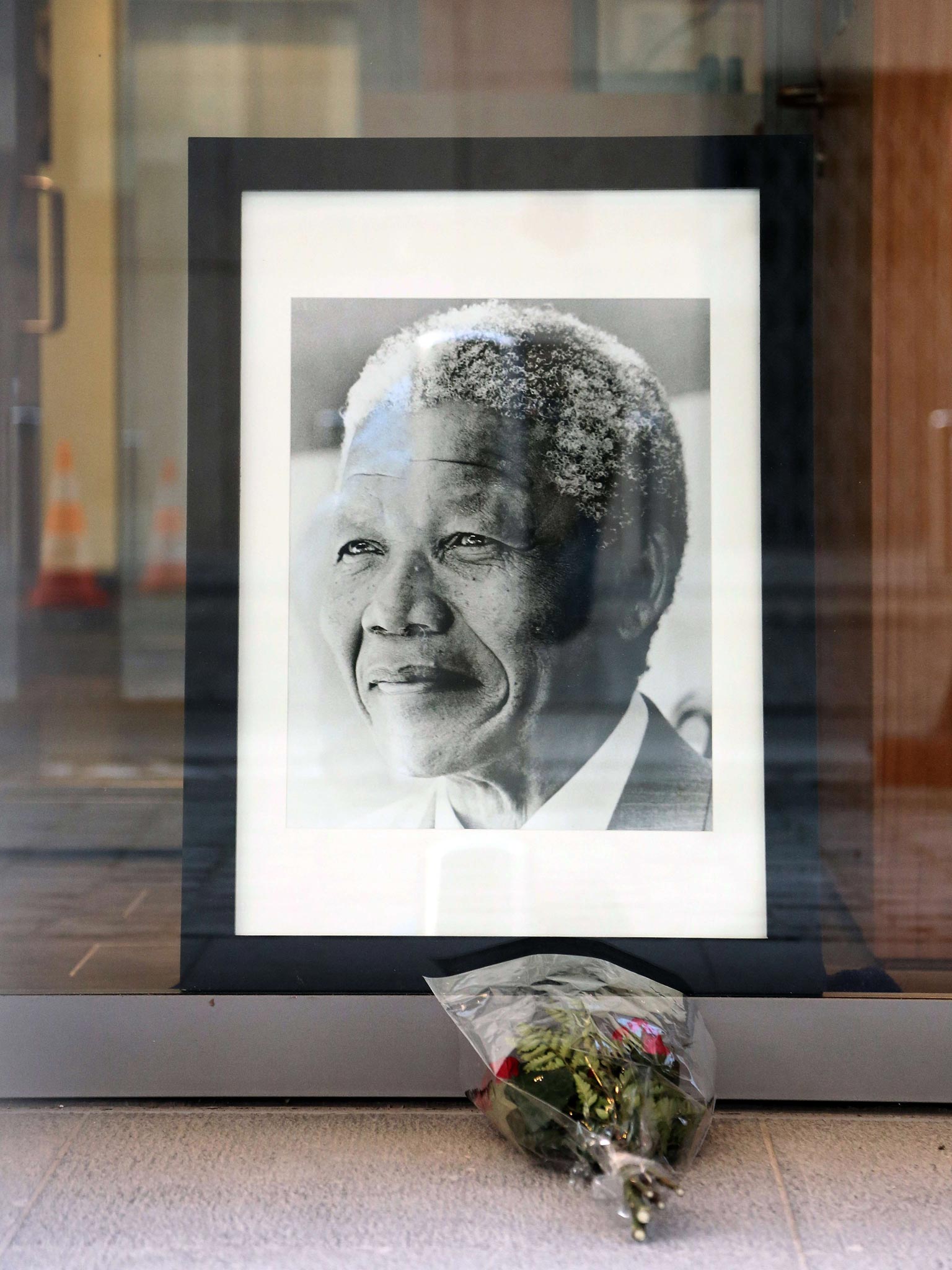 Flowers have been laid in front of a portrait of late Nelson Mandela at the front window of the South-Africa embassy in Brussels