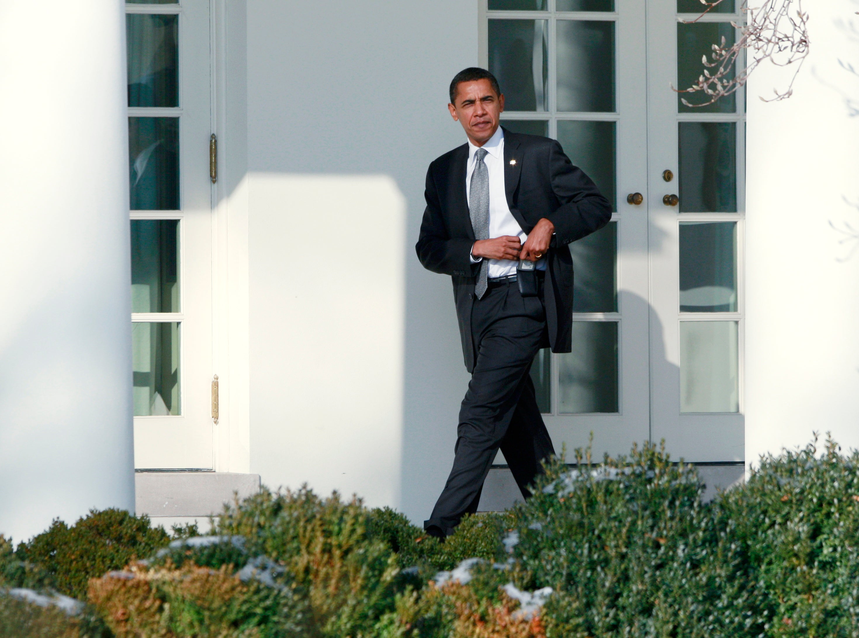 U.S. President Barack Obama places a Blackberry device back in the holster as he makes his way toward the Oval Office at the White House in Washington, January 29, 2009. Obama